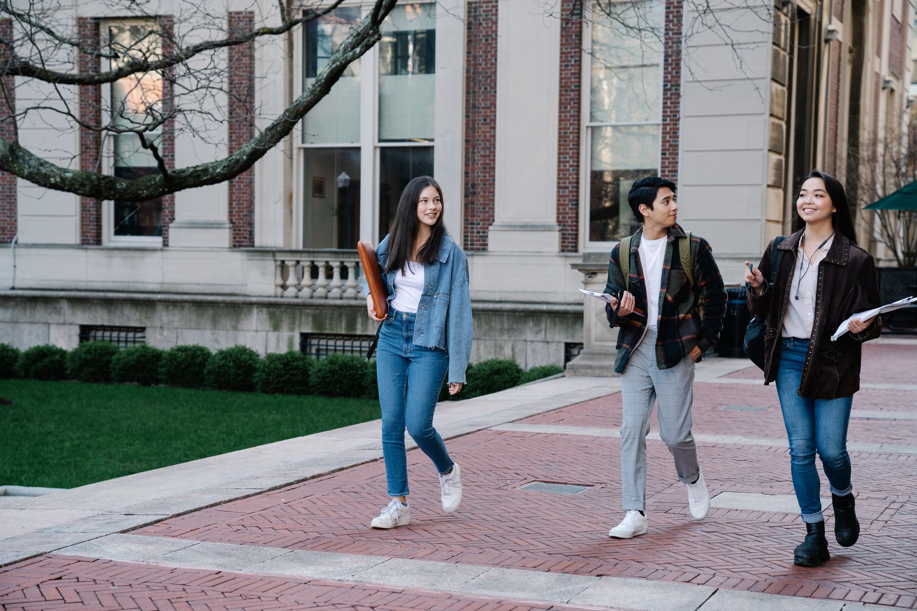 Students walking across a university campus past a main building